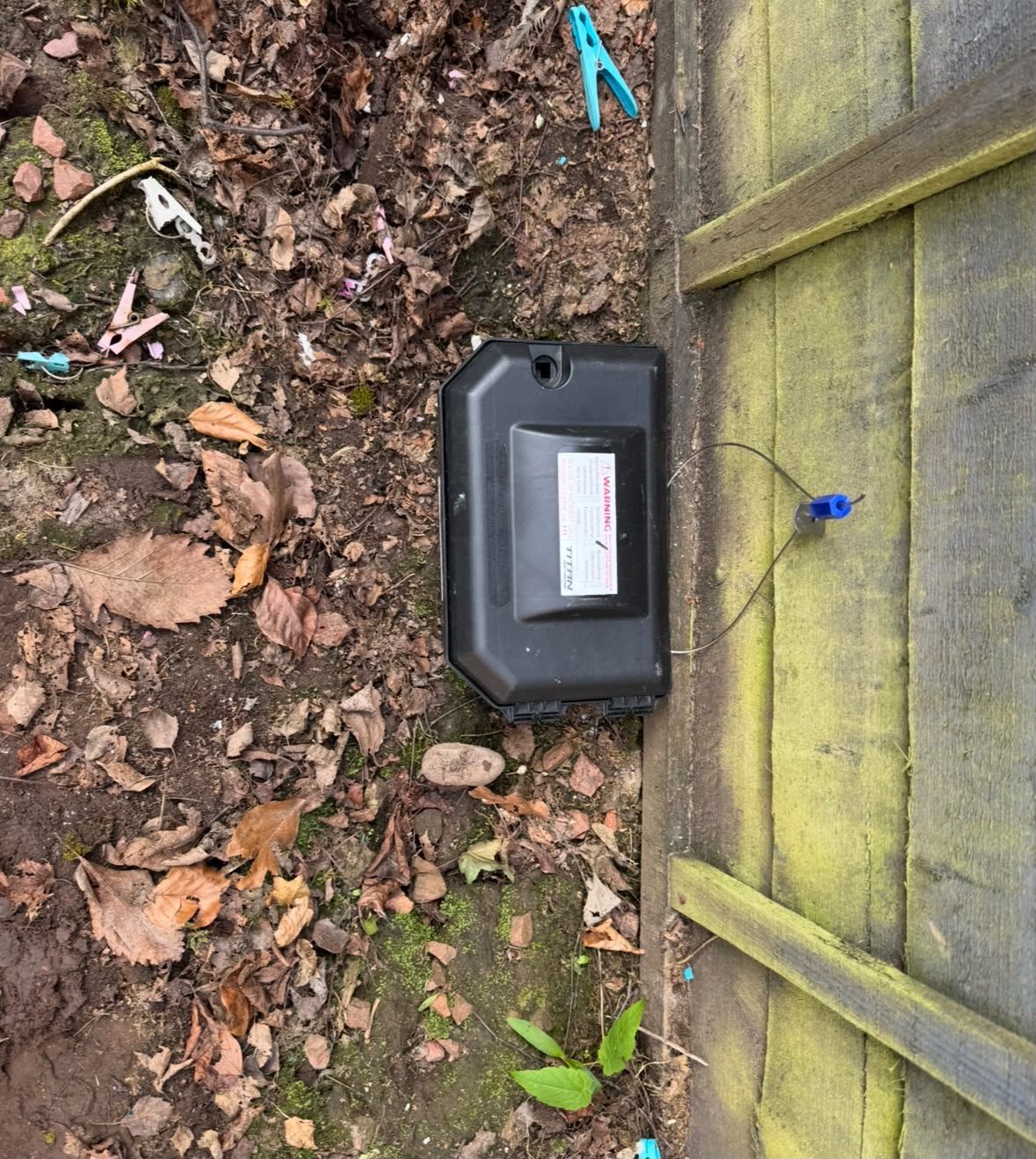 External rat bait station secured to a garden fence line