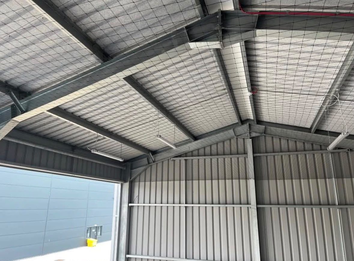 Internal roof netting installed across a warehouse ceiling to exclude birds